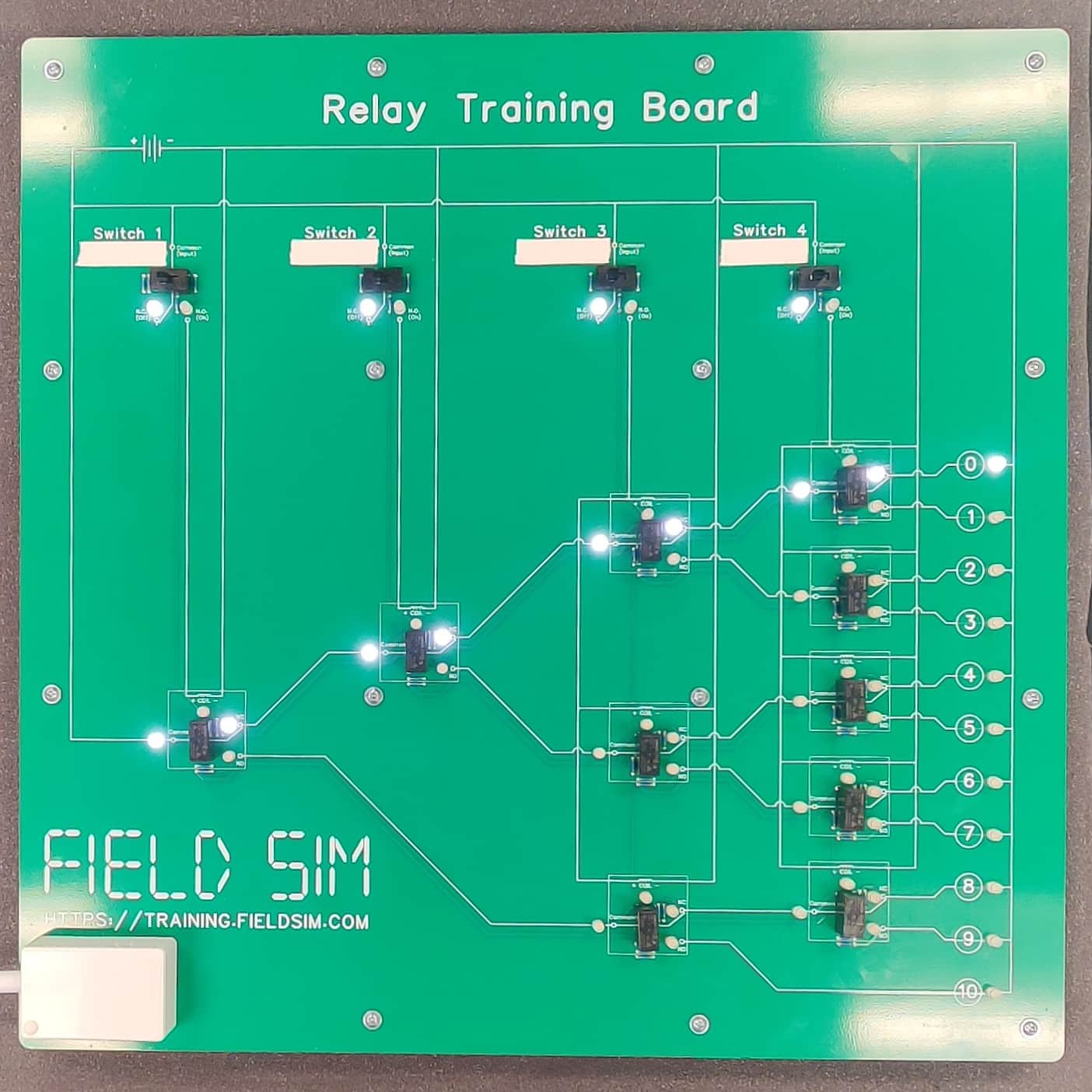 The FS-5-BFT Relay Training Board, showing 4 relays active, 6 relays inactive, LED 0 illuminated, and LEDs 1-10 extinguished.