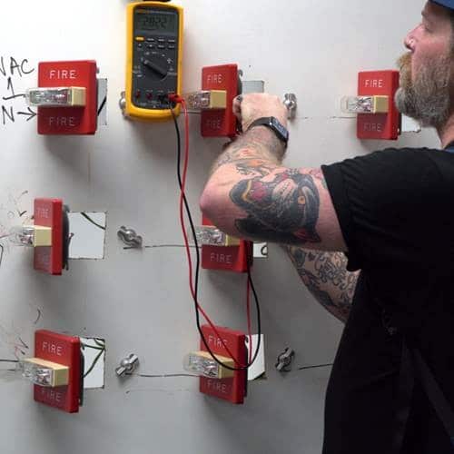A technician using a digital multimeter to measure the voltage on a circuit